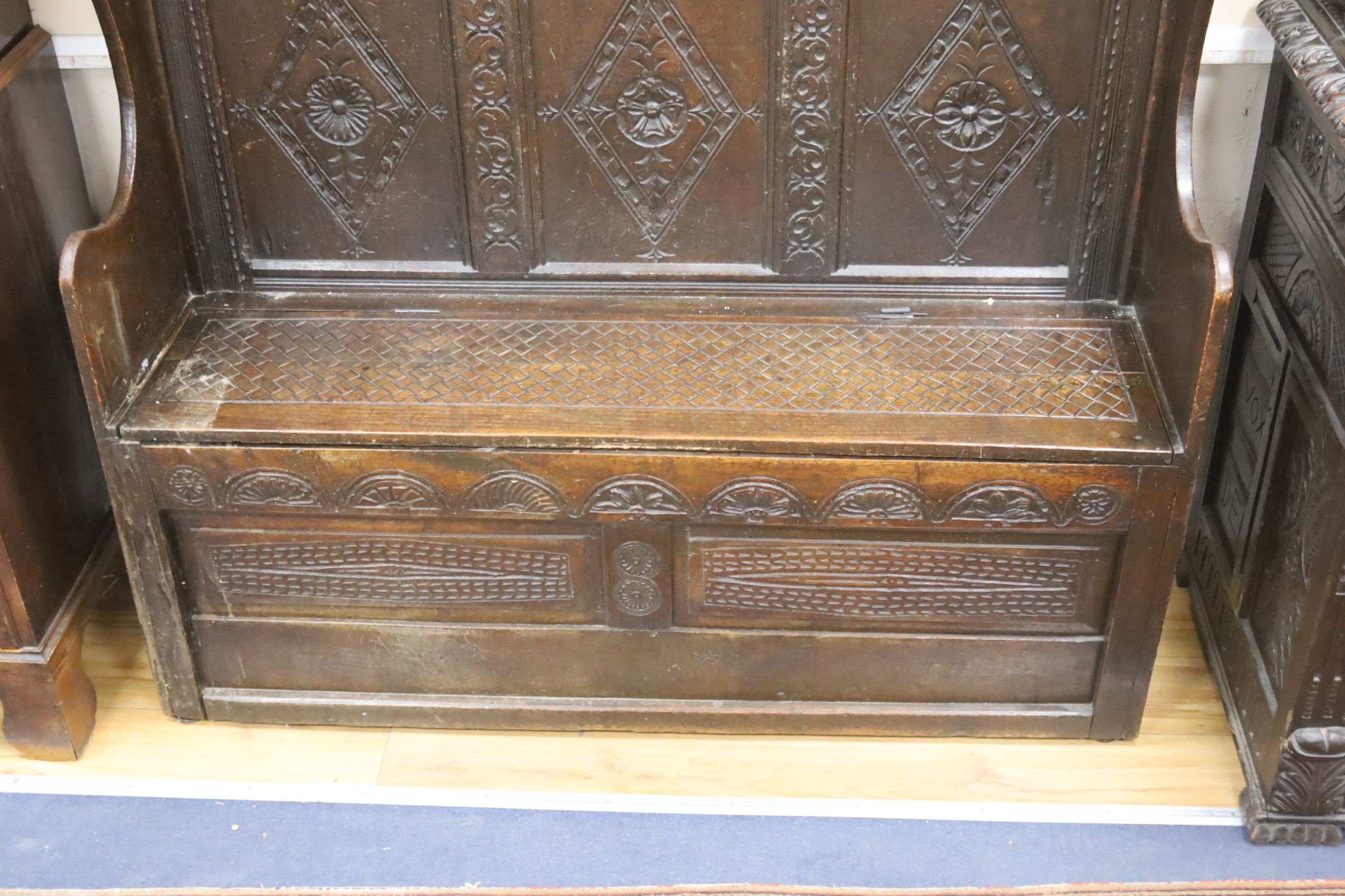 An 18th century and later carved oak settle with hinged box seat, width 137, depth 42, height 137 cms.